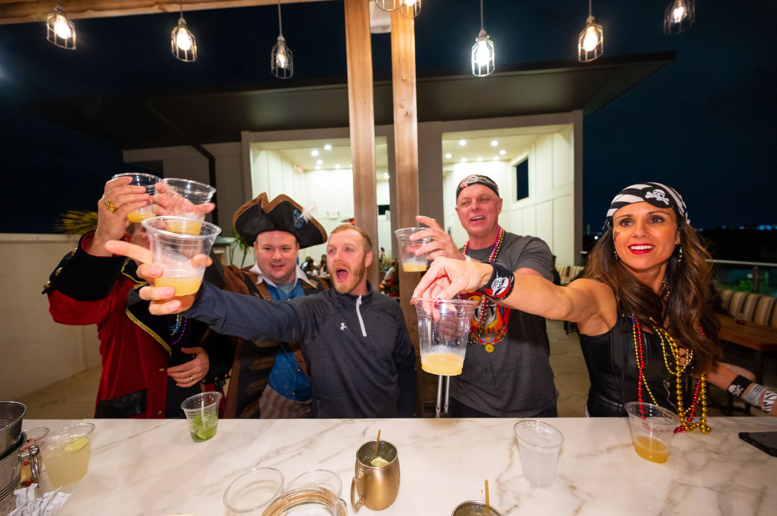 Guests in pirate costumes raising a toast at a themed party