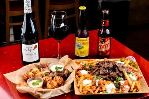 Full table spread of appetizers, wine, and carne asada fries