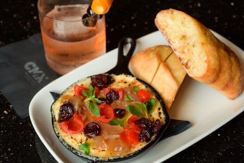 Baked cheese dip with garlic bread and a rose cocktail